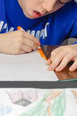 Boy coloring at table with color pencils.
