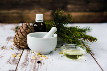 mortar with pine nuts, Cedar knob, Cedar oil and needles on a white wooden table