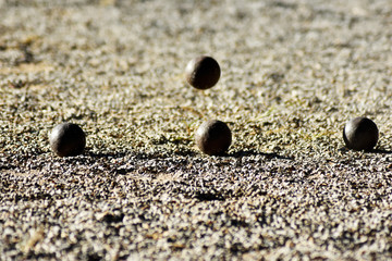 Fototapeta na wymiar Throwing one petanque ball against another ball and impacting many other balls, until the small pebbles bounce along the impact.