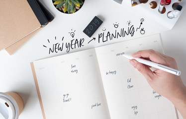 top view of hand writing  new year's planning on open calendar planner with doodle style for life...