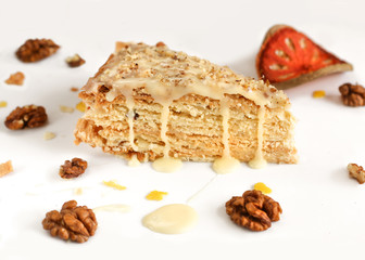slice of puff cake "Napoleon" with walnuts on a white background