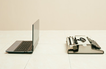 Typewriter and laptop in comparing between low and high business equipment. Concept of technology progress.