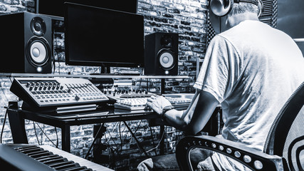 back of male DJ, producer, composer, sound engineer, editor working in sound studio, broadcasting...