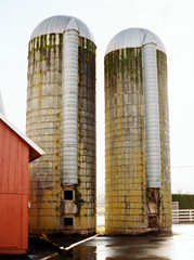 two large silos at sunset next to a red barn