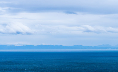 Ocean view from expressway in Asahikawa, Hokkaido, Japan. Mountain and blue sea with cloudy sky.