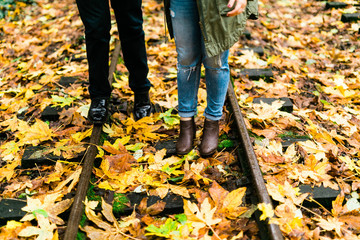 couple walking on train tracks in autumn with leaves on ground