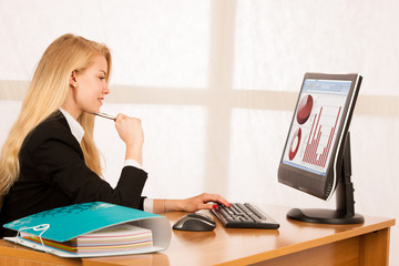 Beautiful young blonde woman working on computer in her office