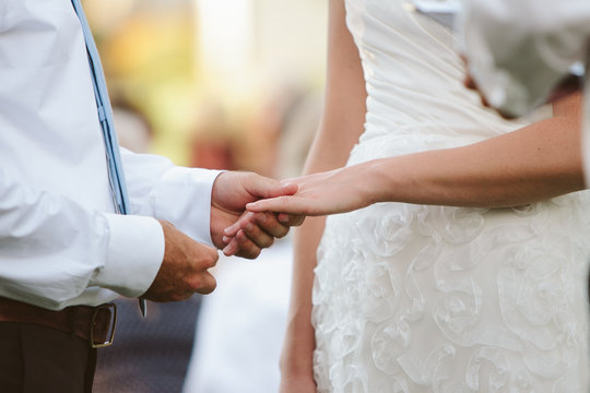 wedding couple holding hands and putting ring on finger