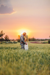 bride and groom kissing in field at a fiery sunset