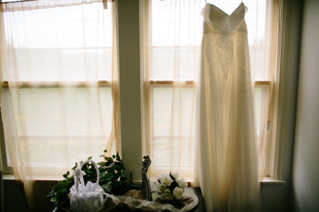 wedding dress hanging above window