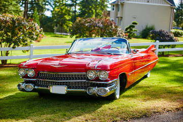front of a red cadillac de ville at sunset sitting on grass