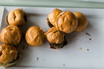 small burger sliders on a plate, a few have been eaten