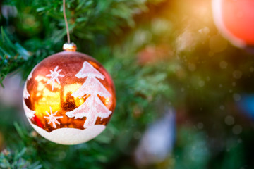 Orange Christmas ball hanging on tree with sunlight shiny