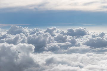 Above fluffy clouds with blue sky from airplane