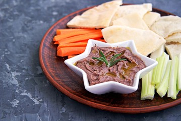 Red bean dip with baked garlic, thyme and olive oil in a star bowl. Served with chopped raw carrots, celery and pita pieces.