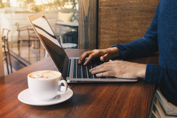 Young business man working at a coffee shop with a laptop.