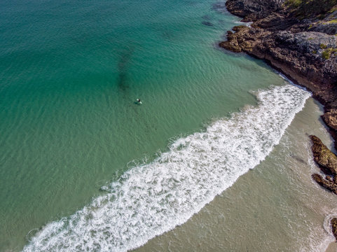 A beautiful drone photo of a surfer waiting for a wave at Puheke beach in the Karikari peninsula, Far North of New Zealand