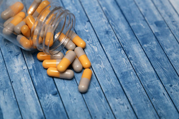 Bottle with pills, medicinal capsules on wooden table. Concept of pharmacy, drugs, antibiotics, vitamins