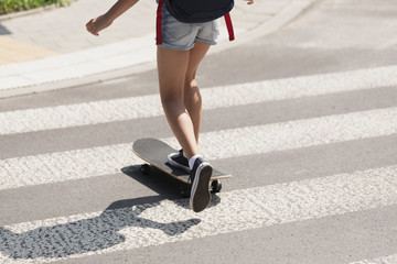 Girl crossing a street on a skateboard