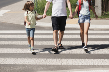 Parent his kids hands while crossing the street