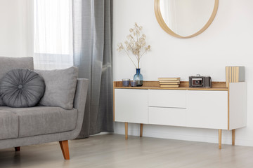 Grey and white living room interior design with mirror, wooden cabinet and grey grey couch