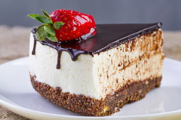 A slice of sweet cake with fresh strawberries and dripping chocolate glaze in a white plate. Sweet dessert. Cake pigeon's milk