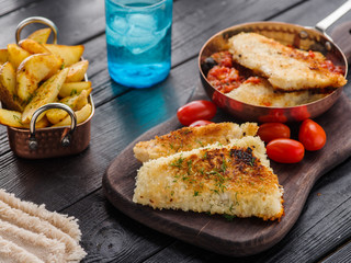 Fried fish with tomato-olive sauce and potatoes.