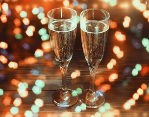 Two glasses of champagne on wooden table in New Year's Eve with bright glitter