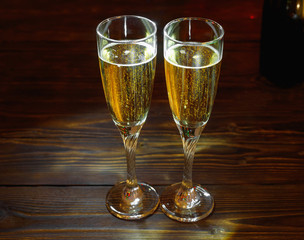 Two glasses of champagne on wooden table in New Year's Eve with bright glitter