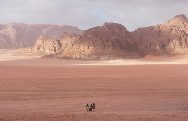 Fototapeta na wymiar Wadi Rum desert landscape in Jordan with tourists riding camels in the morning