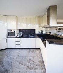 White kitchen with black marble top and large hood