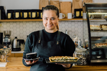 Coffee Business owner concept - friendly young beautiful caucasian female barista in apron smiling...