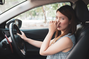 Fototapeta na wymiar Young woman holding her nose because of bad smell in car