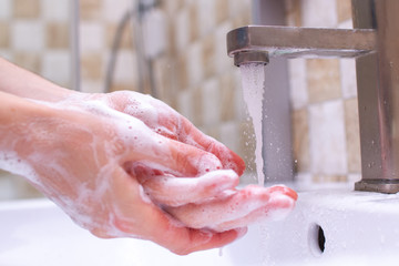 Hand hygiene. Person in the bathroom is cleaning and washing hands using soap foam