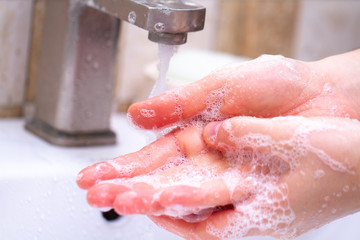 Fototapeta premium Hand hygiene. Person in the bathroom is cleaning and washing hands using soap foam