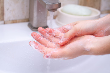 Fototapeta premium Hand hygiene. Person in the bathroom is cleaning and washing hands with soap.