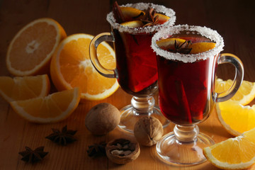 Two cups with ready mulled wine with anise, cinnamon and nuts around