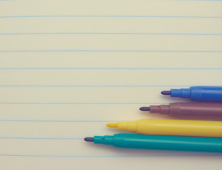 Obraz premium four colored markers on a white Notepad background, close-up, copy space. place for text. school topics. study concept.