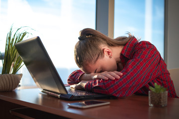 Young business woman fell asleep in the workplace. Feeling overworked and tired from a long working day at the computer