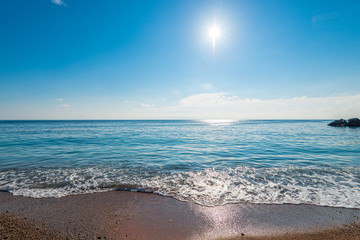 calm blue sea water and bright sun above the horizon