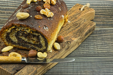 Poppy seed cake with raisins and nuts on an old chopping board