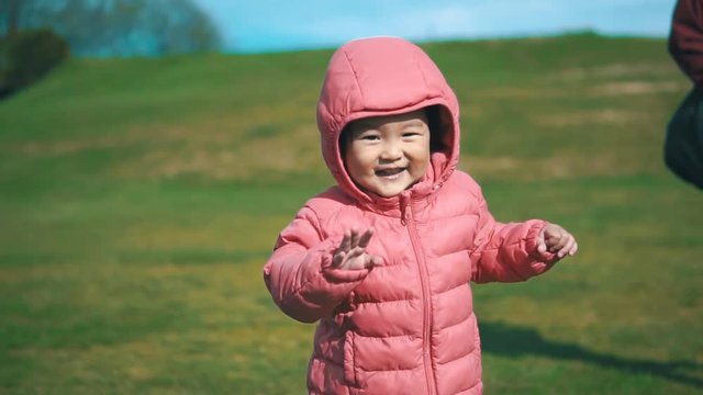Little toddler in pink jacket experiencing running for her first time.