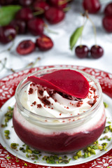 Cherry dessert served on a red and white plate dessert served on a red and white plate, several cherries at the background