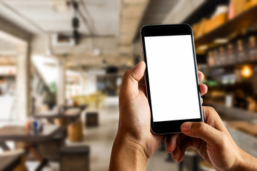 Hand holding white mobile phone with blank white screen  in cafe.
