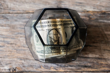 Dollar bills in glass jar on wooden background. Saving money concept