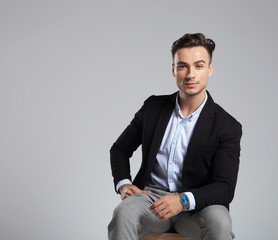 portrait of attractive businessman wearing black suit sitting on chair