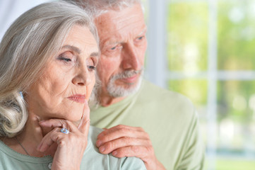 Close up portrait of sad senior couple posing at home