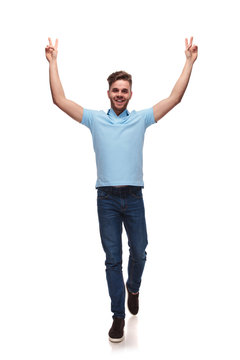 young casual man steps forward while celebrating with victory sign