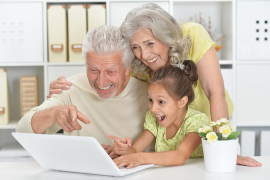 Portrait of grandparents with her granddaughter using tablet