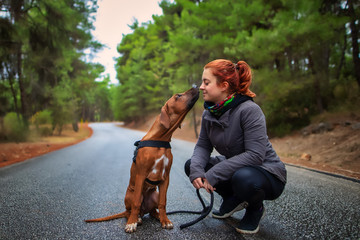 Portrait of happy teenage girl and Rhodesian ridgeback dog . Dog giving girl sweet kiss lick. Love animals love my pet